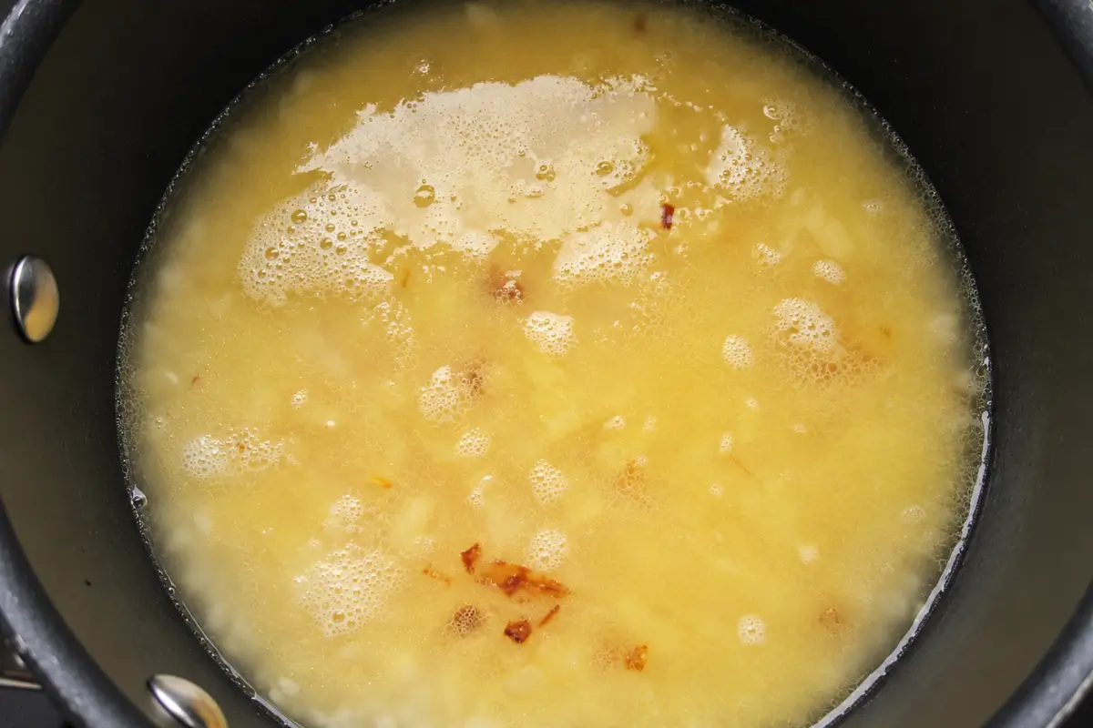 Risotto rice covered with hot stock as it cooks in the pot.