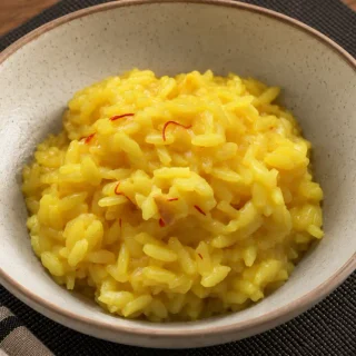 Creamy Risotto alla Milanese with saffron threads served in a bowl.
