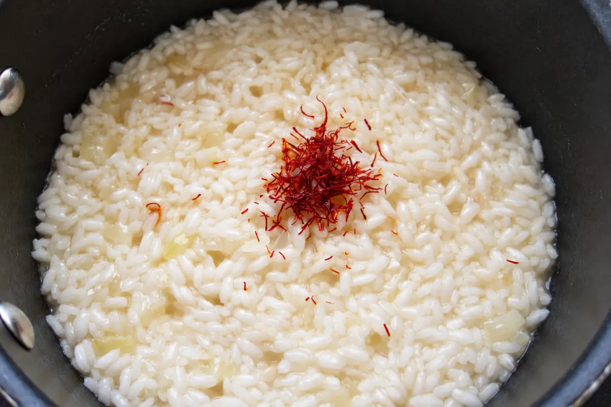 Saffron threads added to partially cooked risotto rice.
