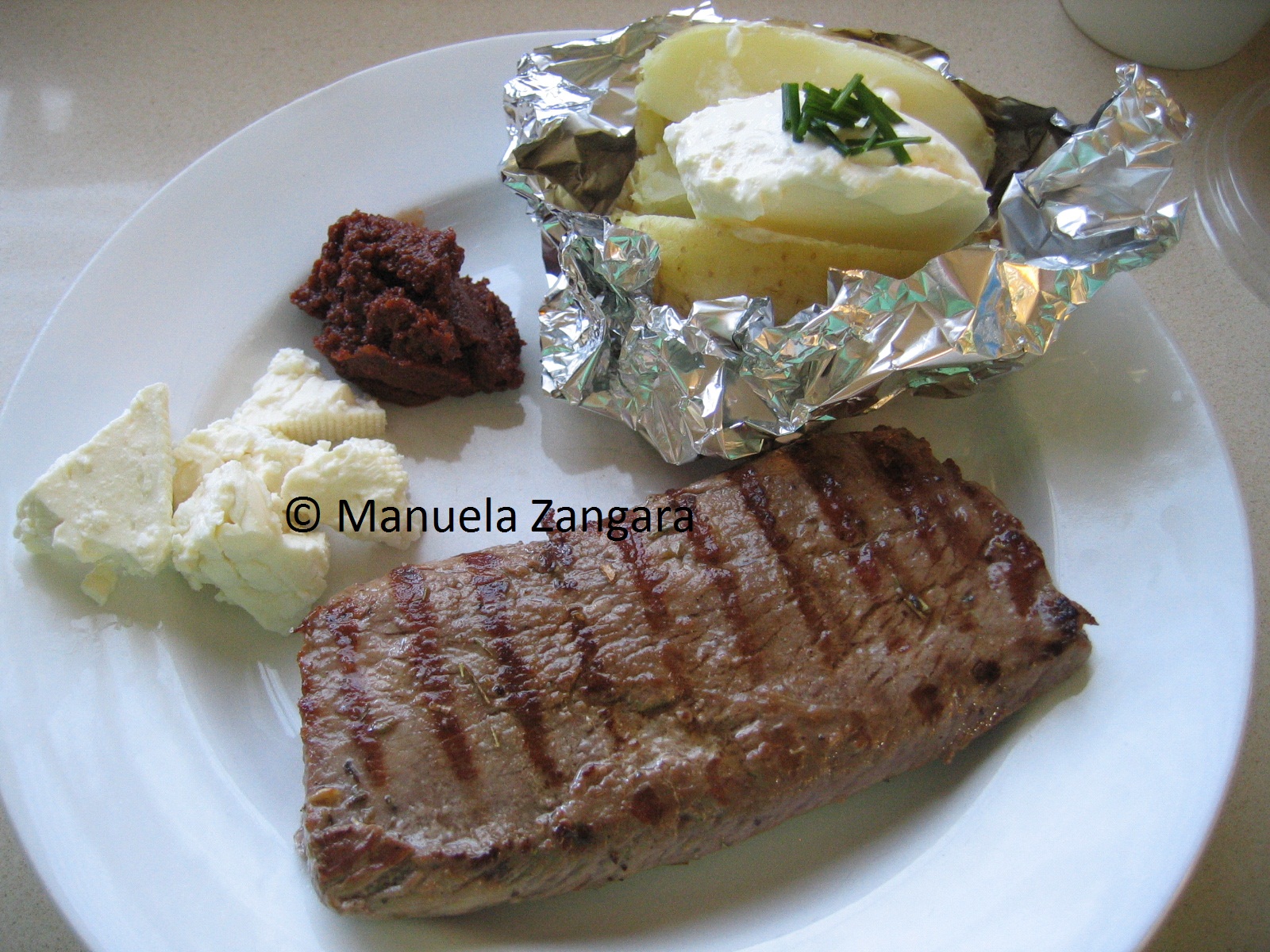 Lamb steak with sun dried tomatoes, feta and baked potato