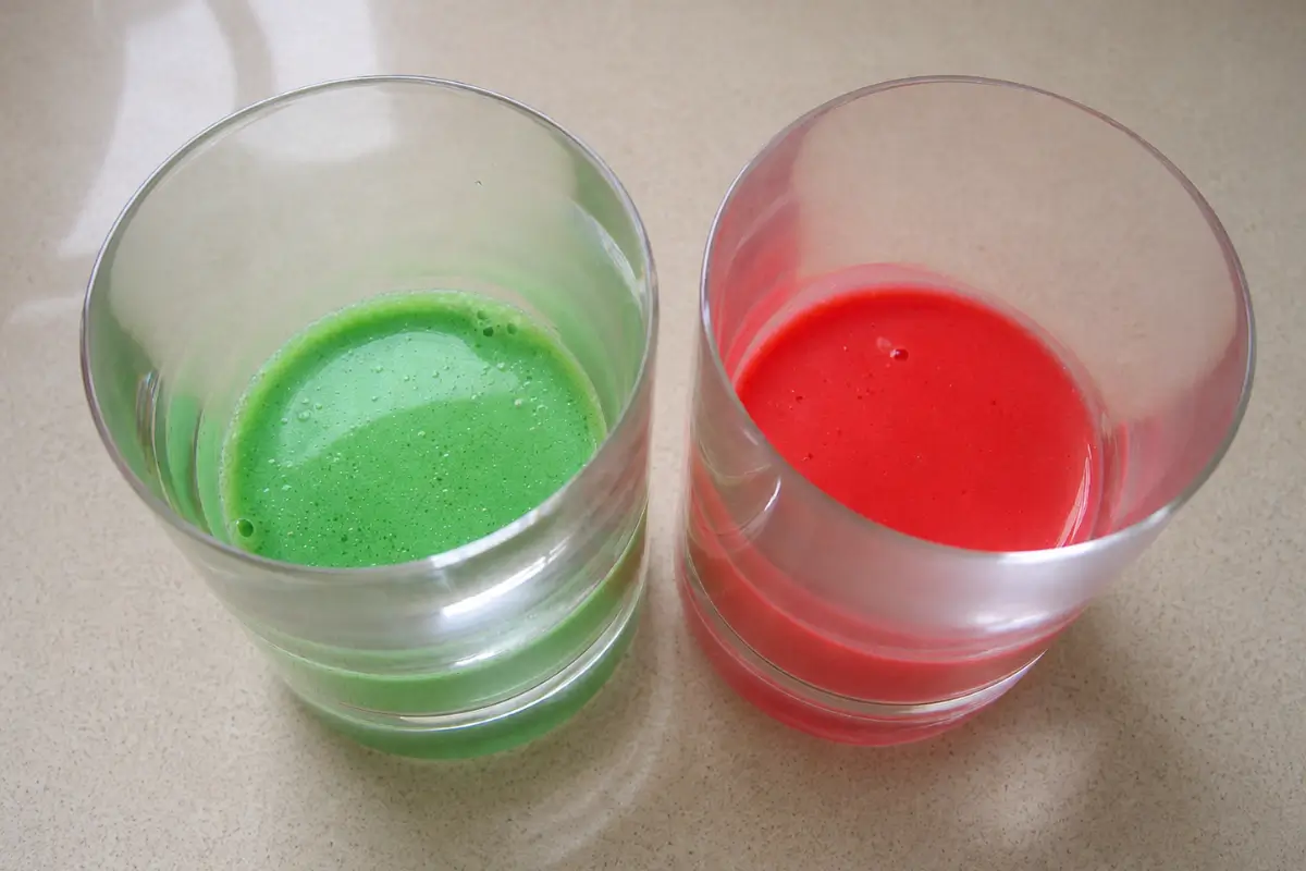 Red and green panna cotta layers chilling in serving glasses before adding the next layer.