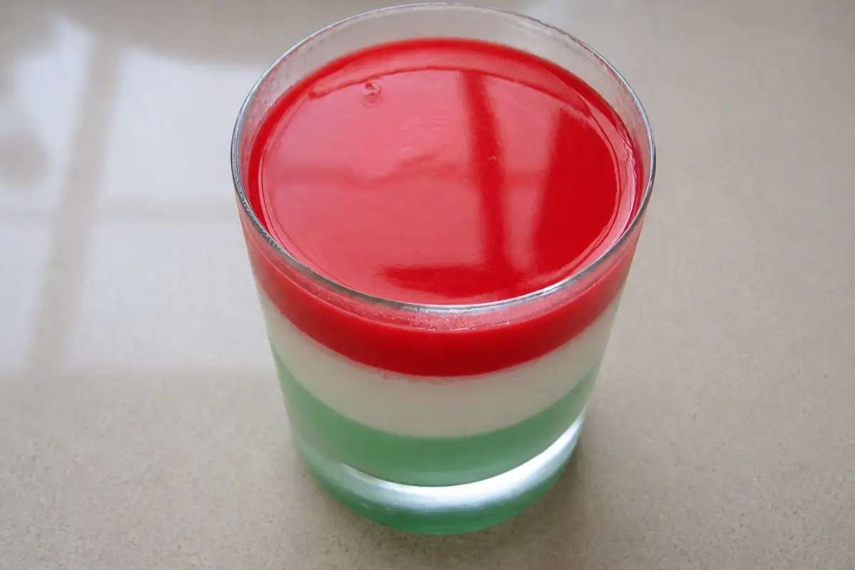 Layered strawberry, vanilla, and mint panna cotta set in a small serving glass before decorating.