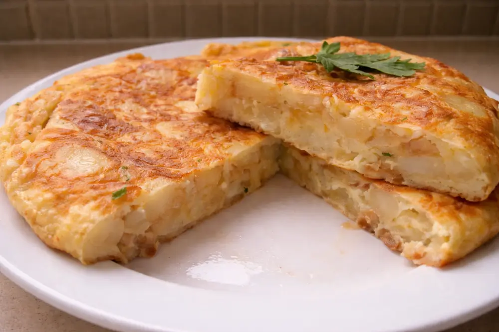 Slice of potato frittata showing a soft interior with tender potatoes and a lightly browned top.