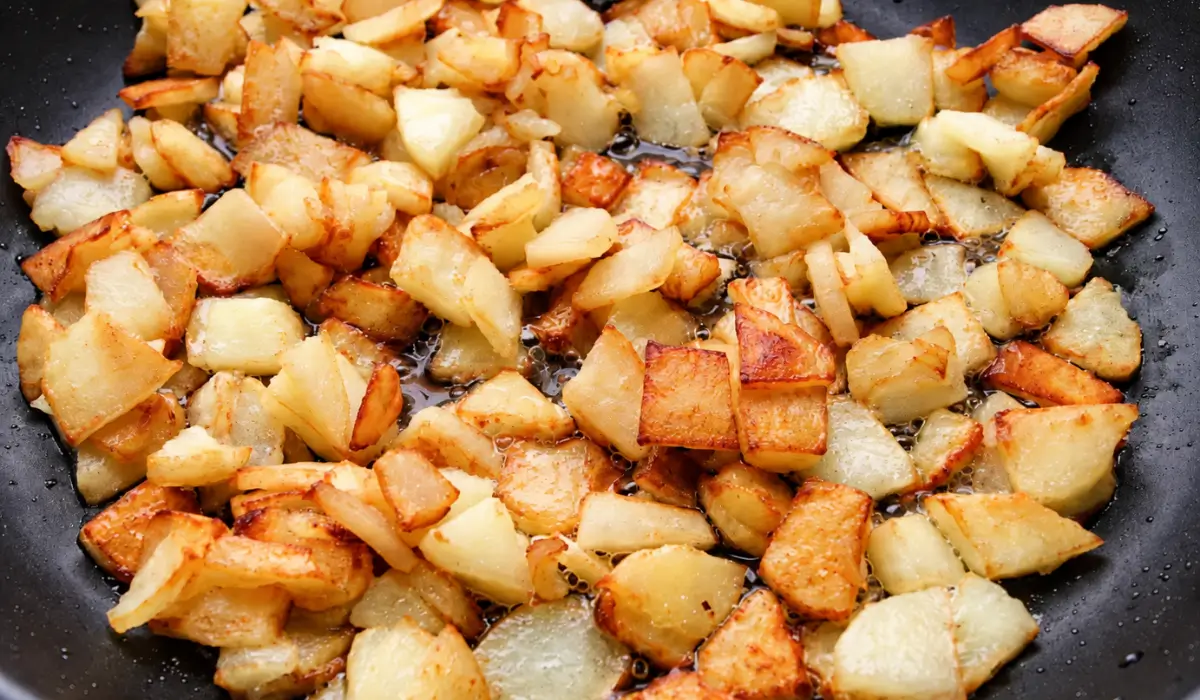 Diced potatoes frying in vegetable oil until golden.