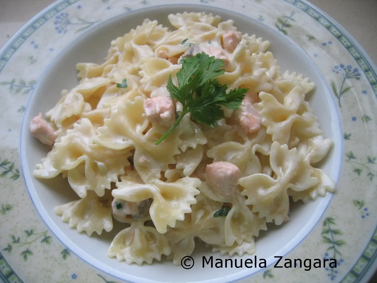 Creamy farfalle pasta with salmon and parsley garnish.