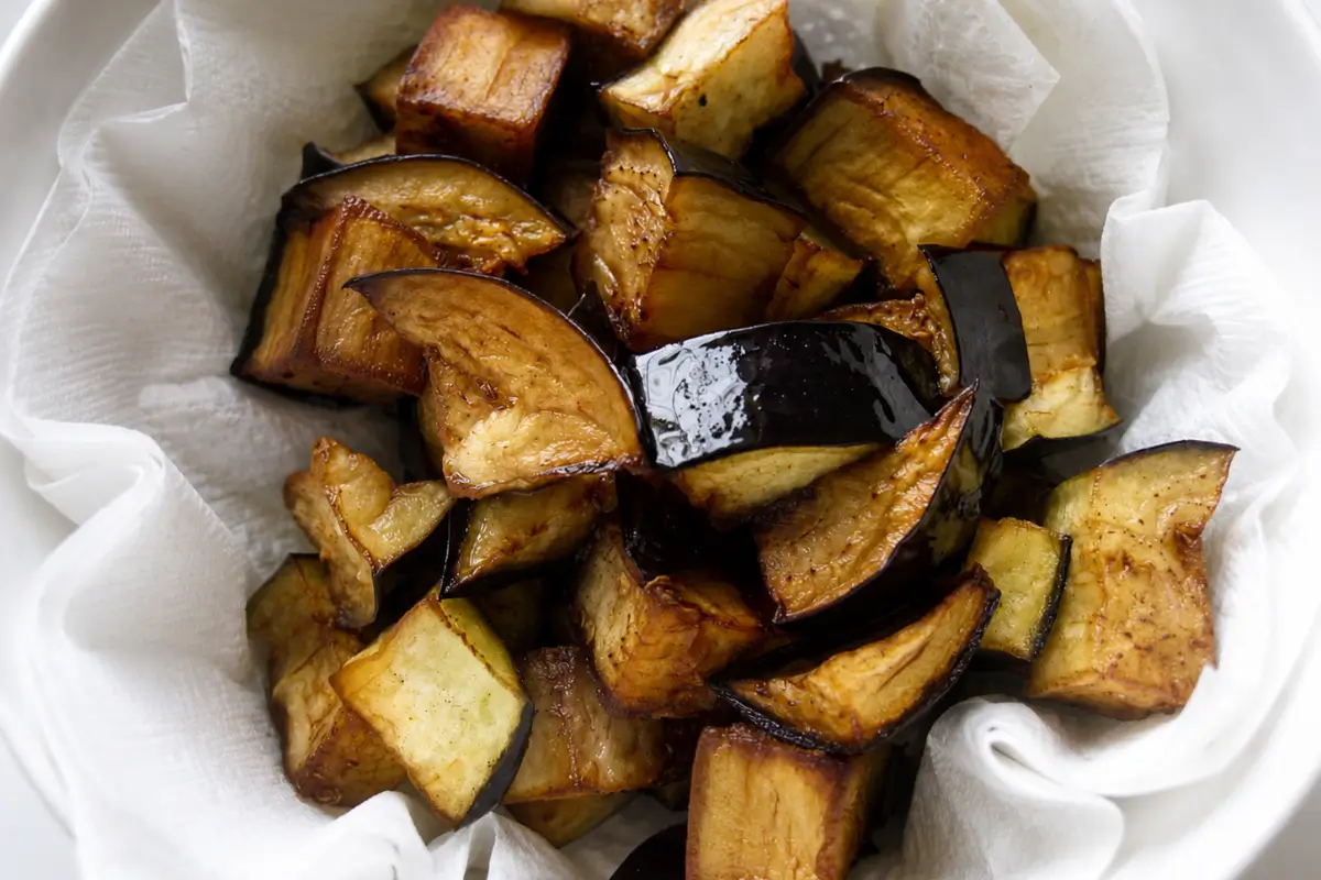 Fried eggplant pieces draining on absorbent kitchen paper.