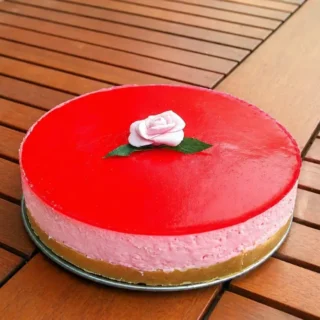 Whole no-bake cheesecake with glossy rose topping and fondant rose decoration.