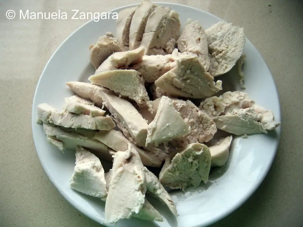 Sliced poached chicken breasts arranged on a white plate.