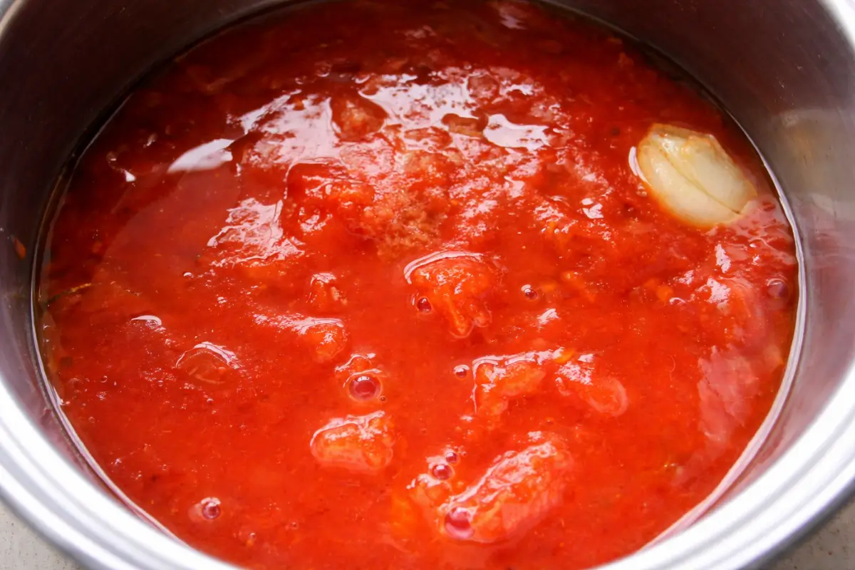 Tomato sauce with garlic simmering in a pan before thickening.