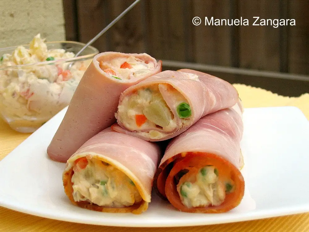 Russian Salad in Ham Cannoli Close-up of Russian Salad wrapped in ham slices and served on a white plate.