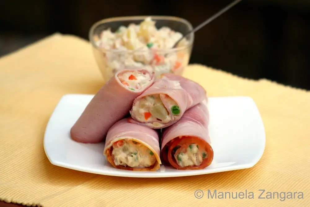 Rolled ham slices filled with creamy Russian Salad served on a white plate.