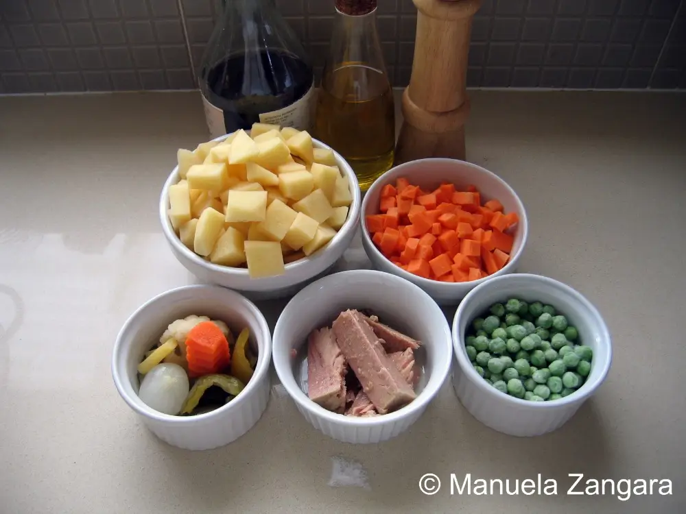 Ingredients for Insalata Russa arranged in small bowls.