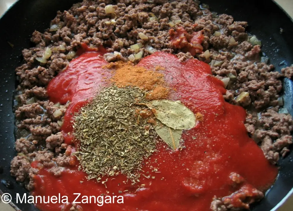 IMG_0468 Tomato purée, herbs, and a bay leaf added to browned mince in the pan.