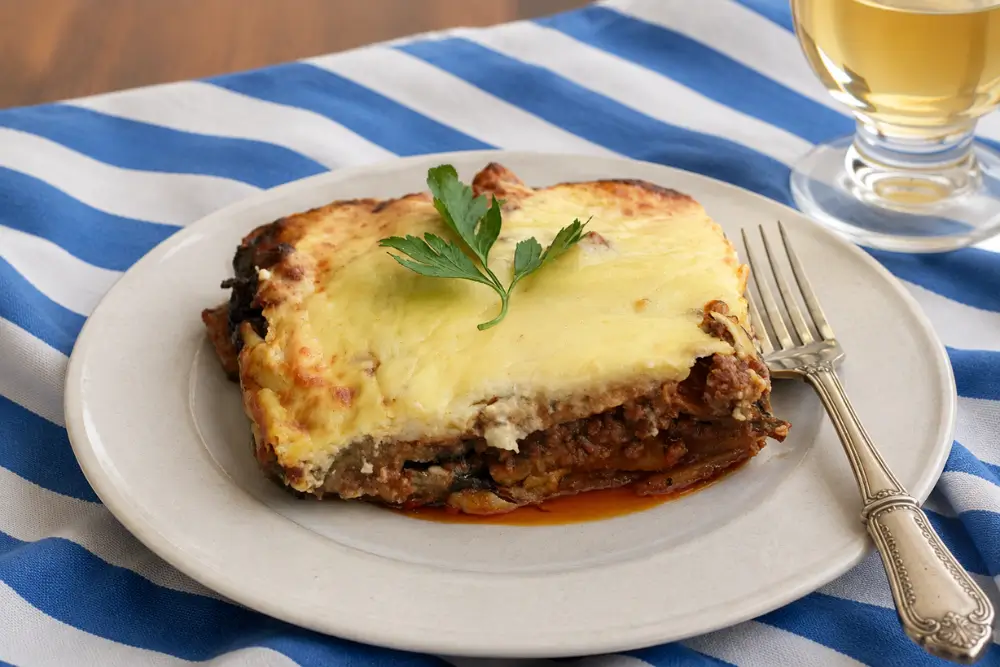 Moussaka Layered eggplant casserole with a golden béchamel topping and parsley.