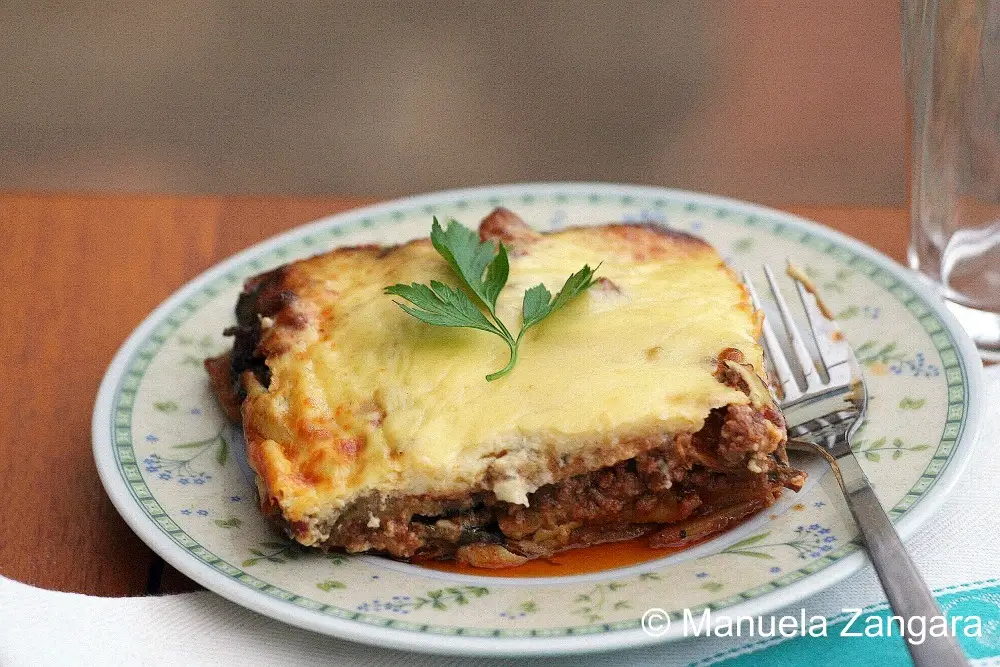 Moussaka A plated slice of moussaka with a glass on a table.