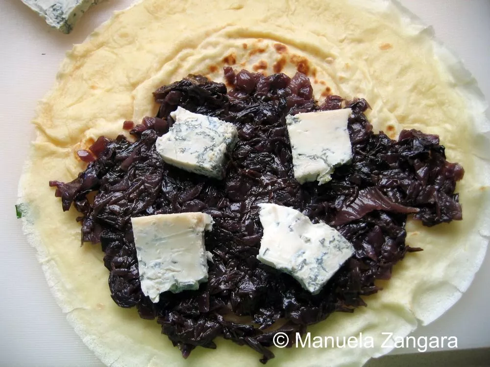 Crespella topped with cooked radicchio and pieces of gorgonzola before folding.