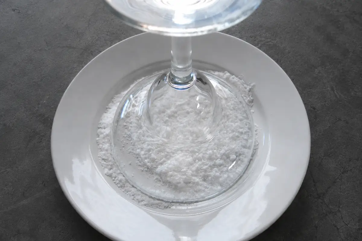 Margarita glass rim being dipped into salt on a plate.