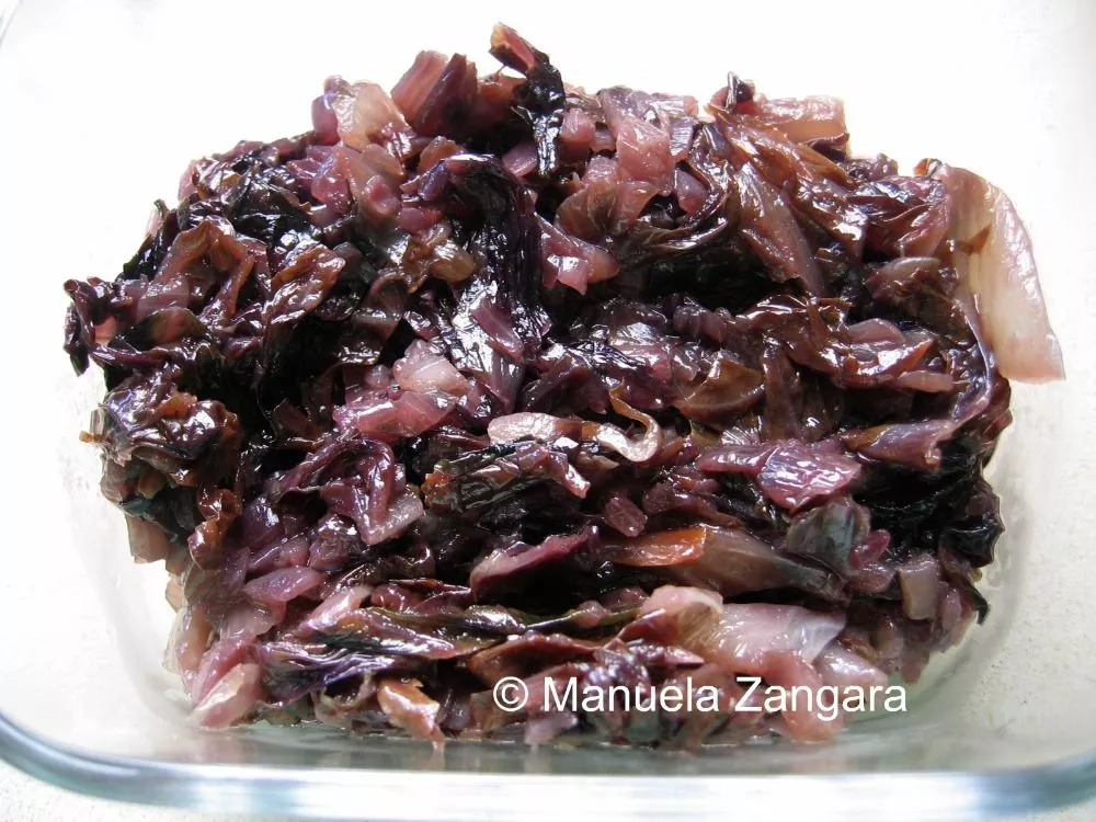 Sautéed radicchio and onion mixture cooling in a glass dish.