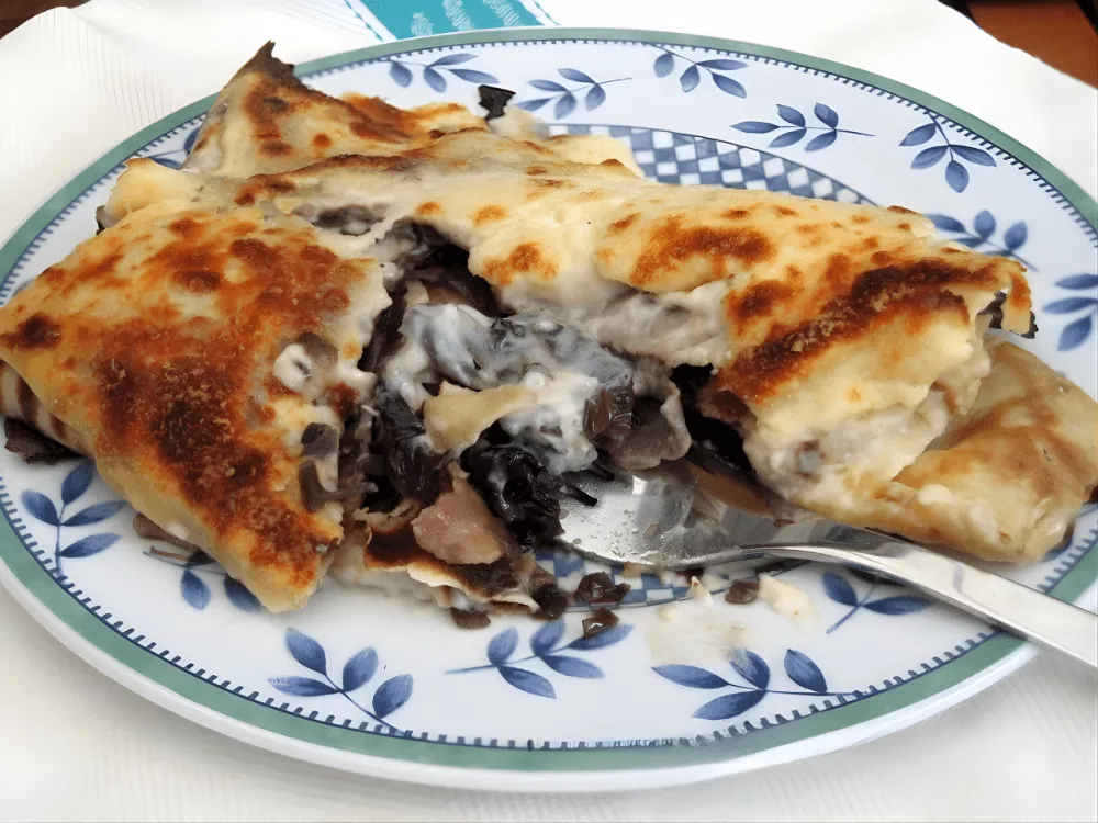 Baked stuffed crespelle filled with radicchio and gorgonzola served on a plate.