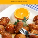 Homemade Orange Chicken served with steamed rice, sesame seeds, and an orange slice garnish.