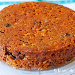 Baked anelletti pasta cake on a glass plate.