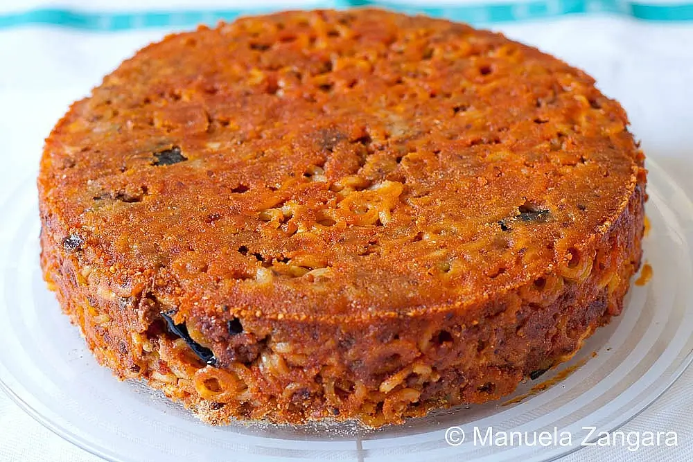 Baked anelletti pasta cake on a glass plate.
