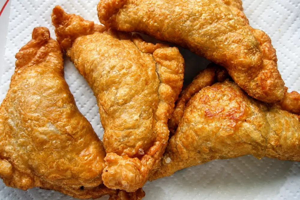 Golden baked curry puffs with flaky pastry on a plate.