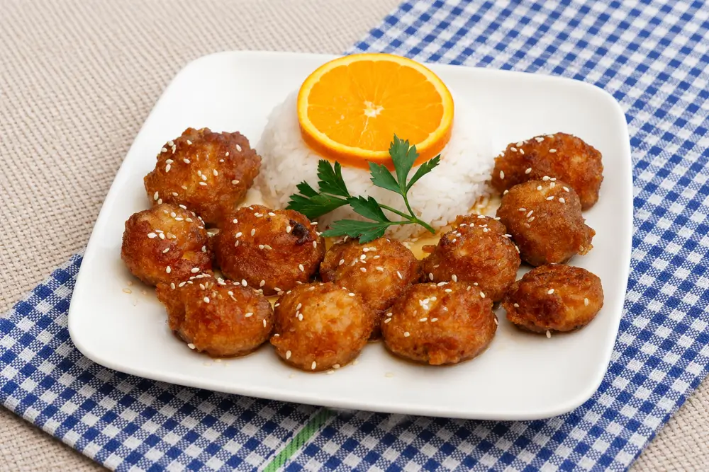 Better than takeout Orange Chicken served with rice and sprinkled with sesame seeds.