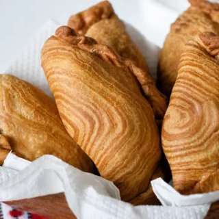 Crisp flaky pastry with visible layers on freshly fried curry puffs.