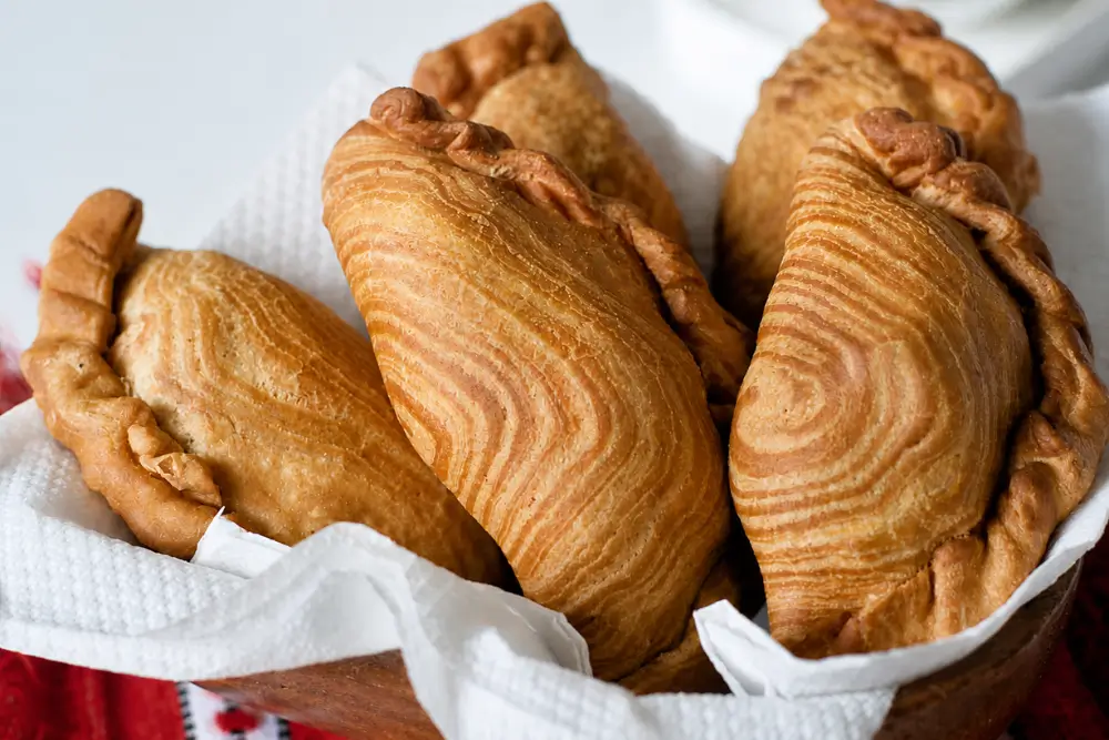 Crisp flaky pastry with visible layers on freshly fried curry puffs.