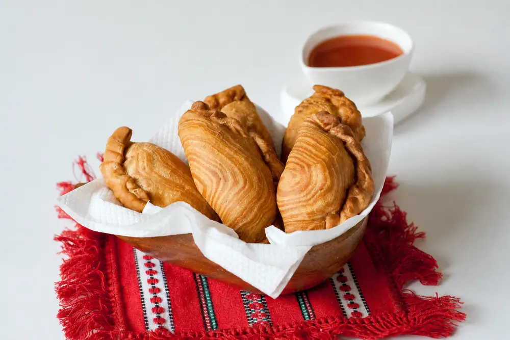 Homemade Curry Puffs served warm with sweet chilli sauce.