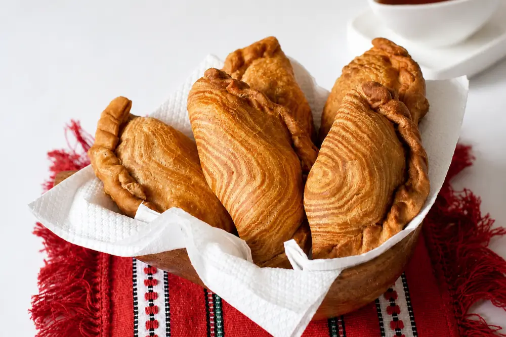 Golden curry puffs with crisp flaky pastry layers in a bowl.
