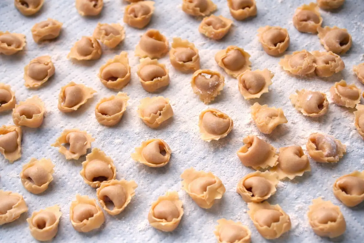 Fresh tortellini arranged on a floured surface before cooking.