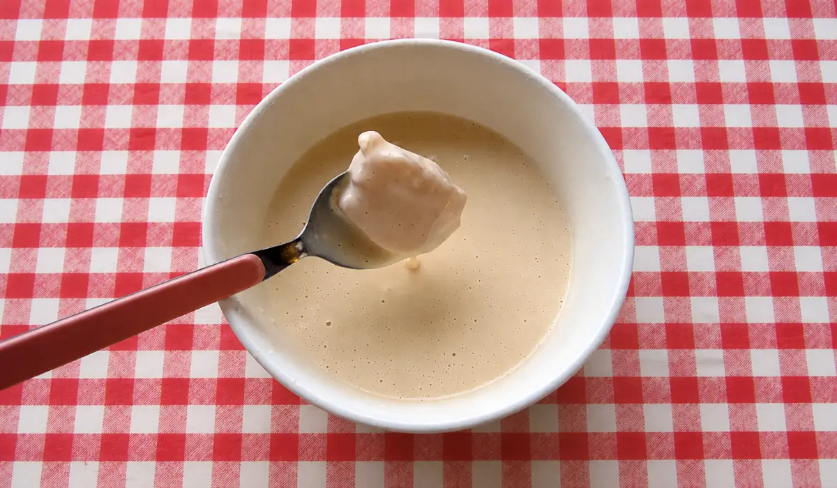 Smooth batter coating a piece of chicken before frying.
