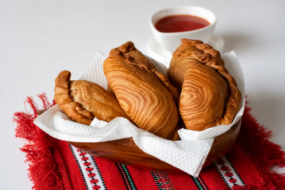 Thai curry puffs served warm in a wooden bowl lined with kitchen paper.