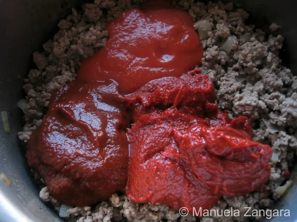 Tomato purée, double concentrate, and estratto added to browned meat.