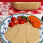 Plate of Vitello Tonnato covered with creamy tuna sauce and served with cherry tomatoes, basil, and carrot slices.