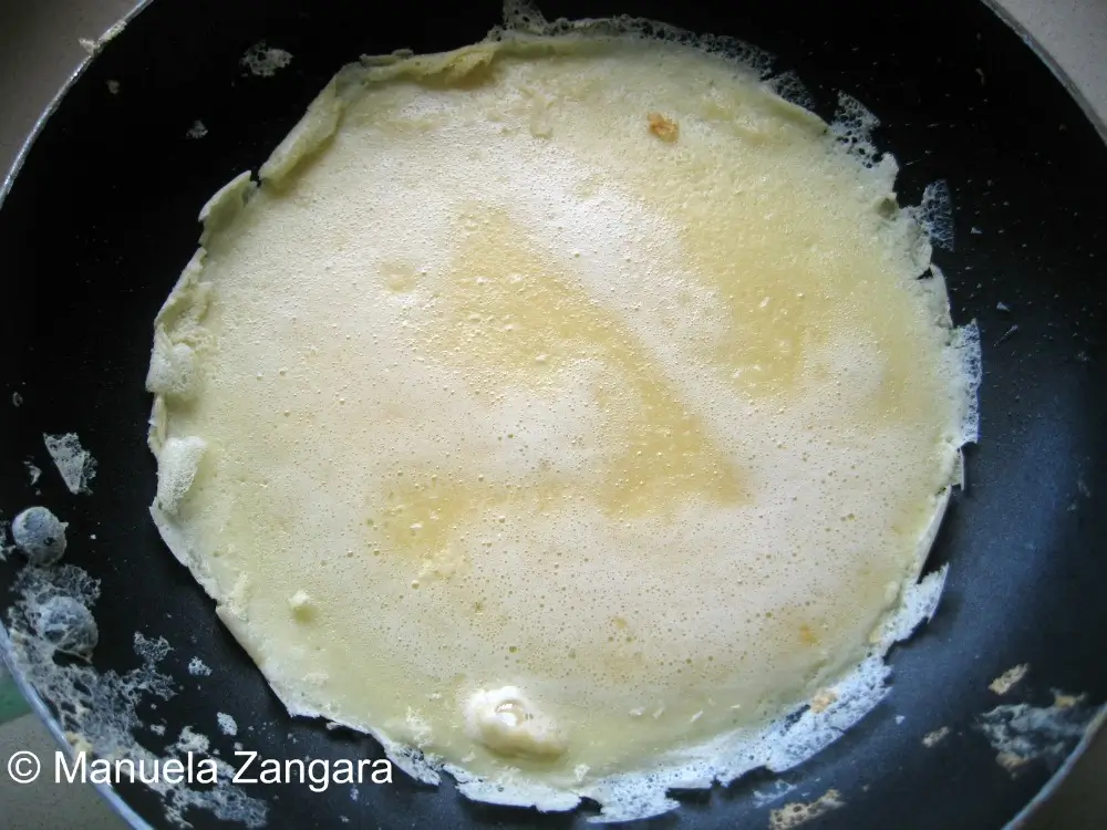 Egg batter cooking in a non-stick pan before flipping.