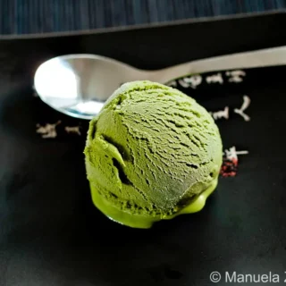 Close up of creamy green tea gelato scoop on dark plate.