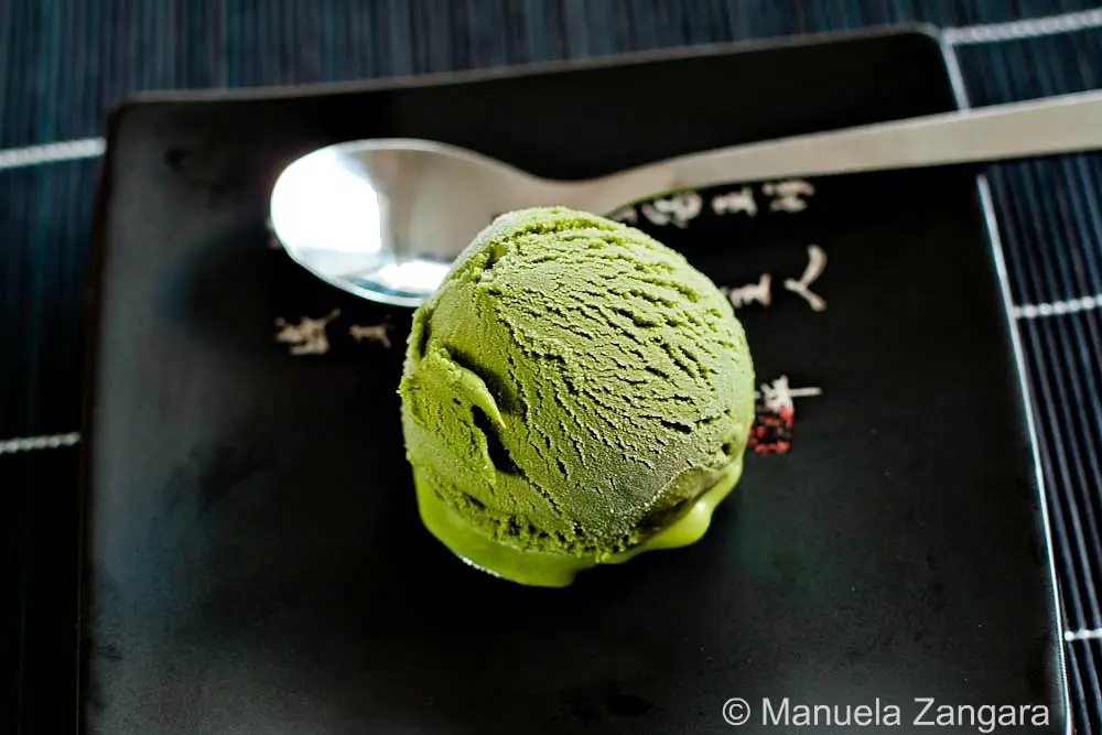 Close up of creamy green tea gelato scoop on dark plate.