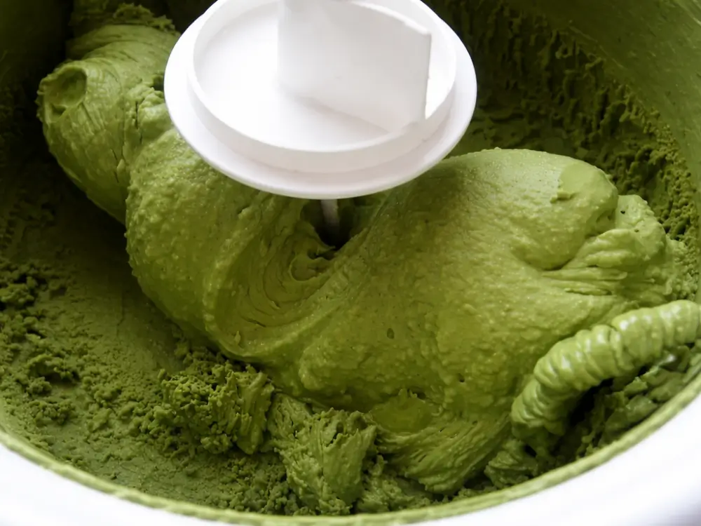 Thick green tea mixture churning inside an ice cream maker.