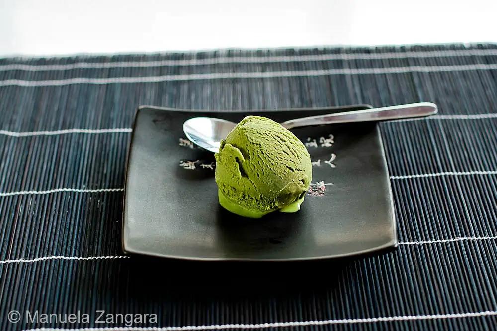 Single scoop of Matcha Ice Cream served on a black square plate with spoon.