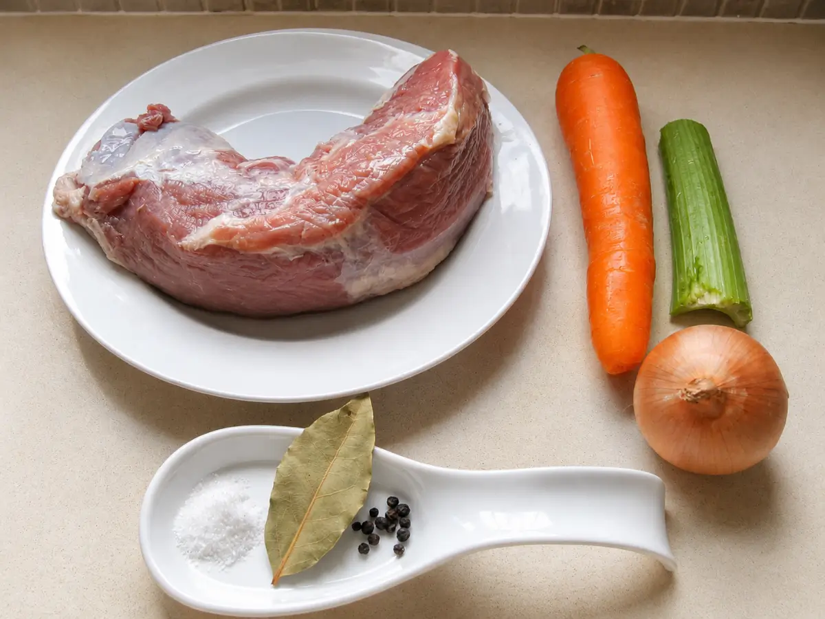 Veal girello with carrot, celery, onion, bay leaf, salt, and pepper corns prepared for Vitello Tonnato.