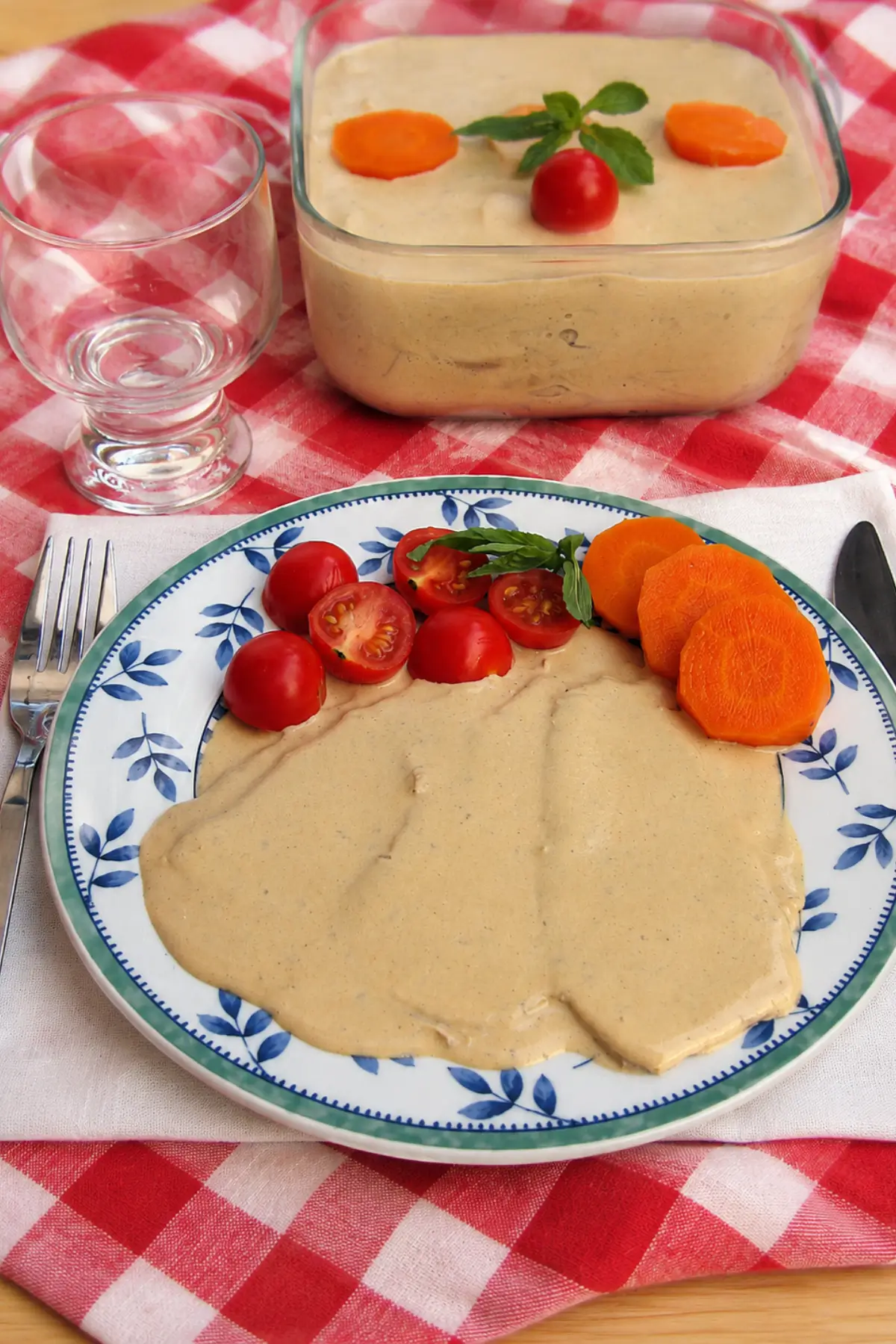 Plate of Vitello Tonnato covered with creamy tuna sauce and served with cherry tomatoes, basil, and carrot slices.