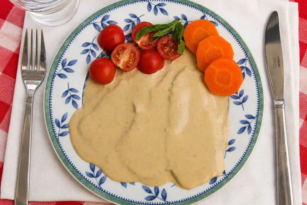 Vitello Tonnato covered with creamy tuna sauce and decorated with carrot slices and cherry tomatoes.
