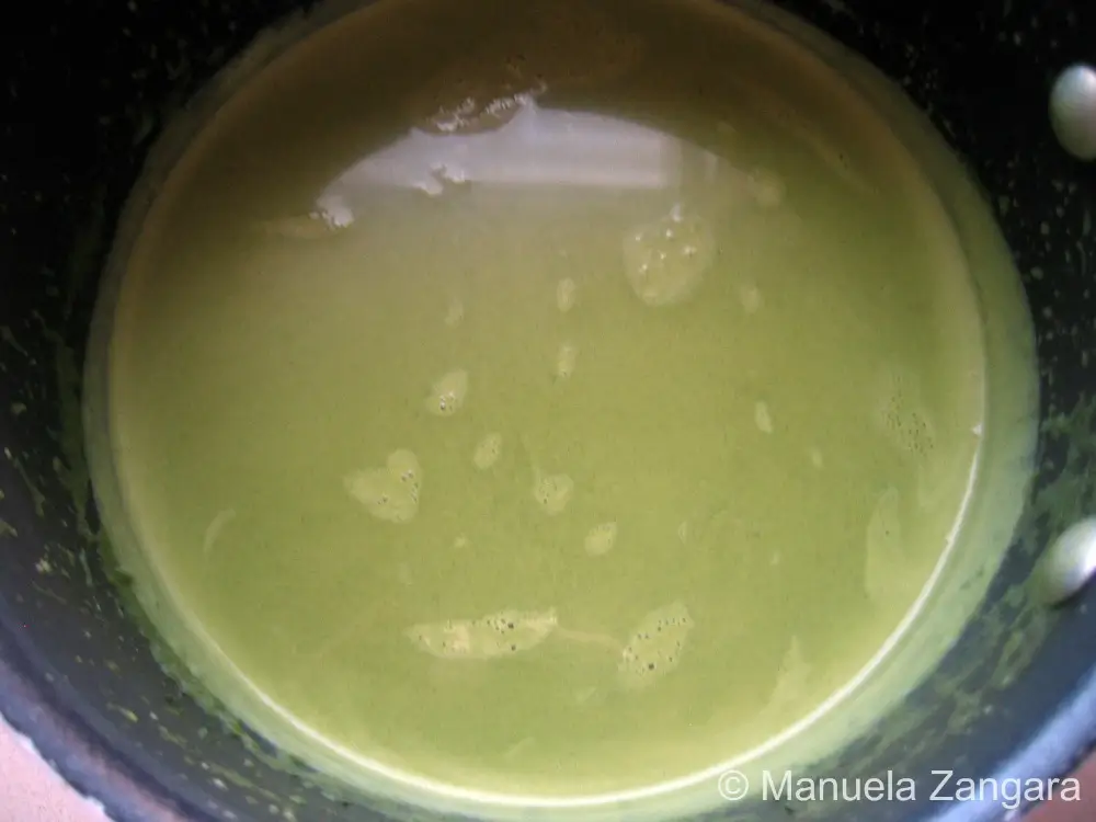 Whisk blending warm cream and matcha until smooth and foamy.