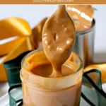 Thick, creamy Dulce de Leche in a glass jar with a spoon and golden ribbon.