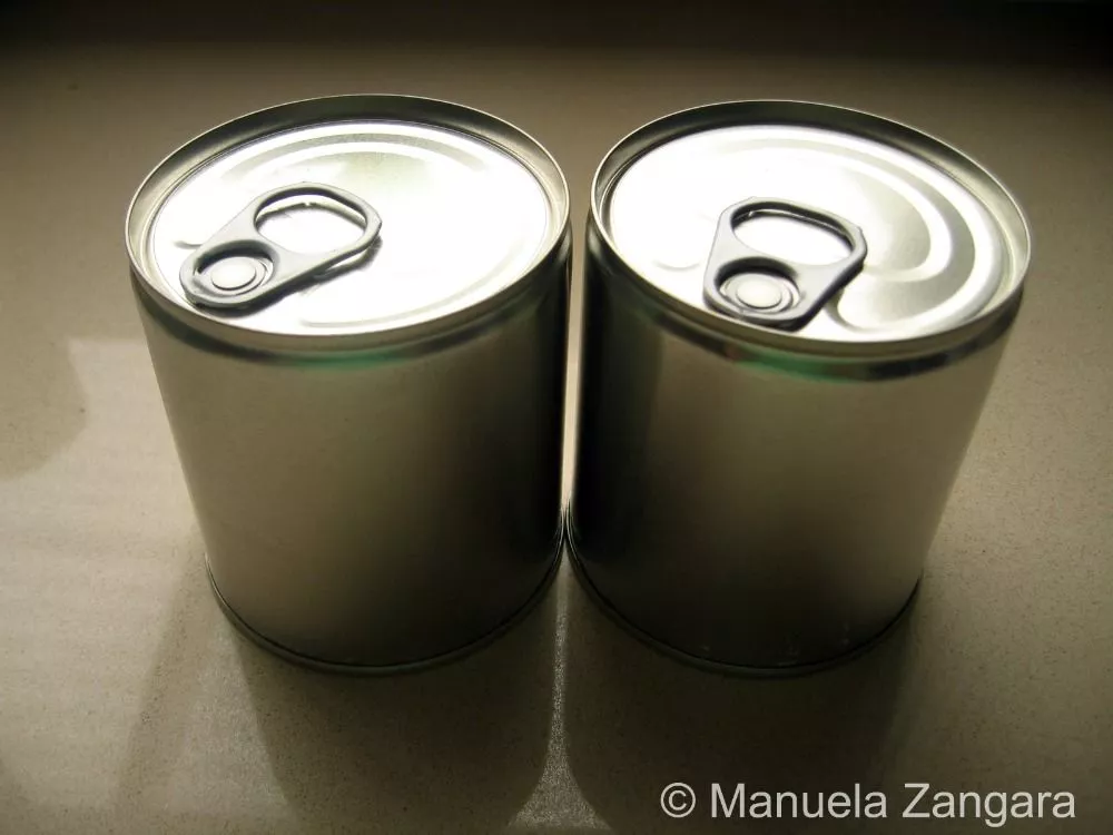 Two unopened tins of sweetened condensed milk on a kitchen counter.