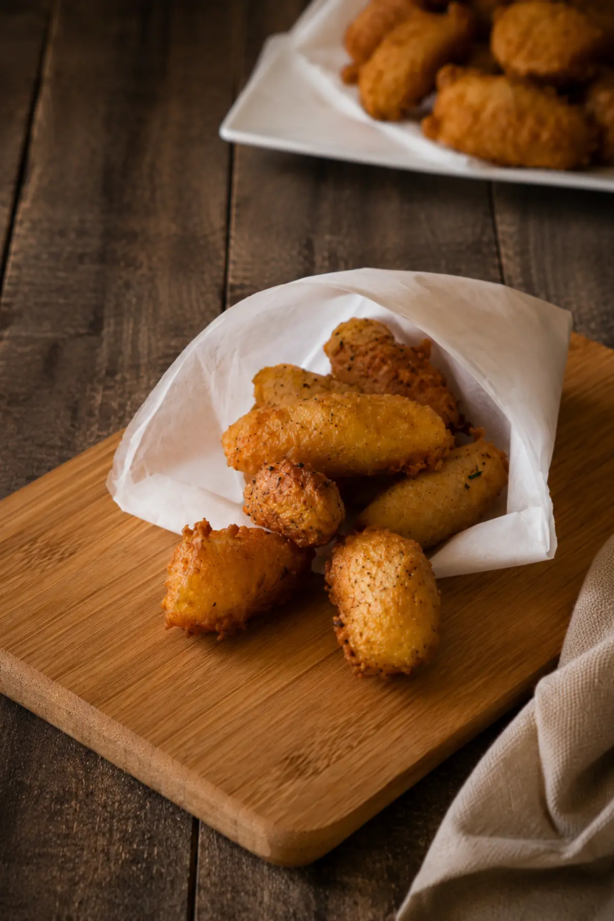 Fried cazzilli served hot in a paper cone on a wooden board.
