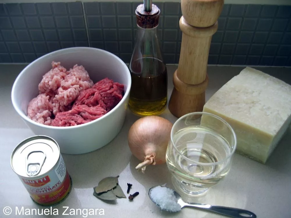 IMG_0607 A plate of sliced bread, cheese, meat sauce, egg, flour, and breadcrumbs.